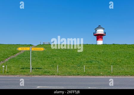 Un faro rosso e bianco sovrasta una diga in Alte Land vicino a Lühe, Germania Foto Stock