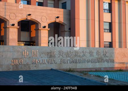 Yerevan, Armenia - 27 ottobre 2022: Scuola di amicizia armeno-cinese, scritta sul muro in armeno e mandarino. La luce del sole dona alle pareti un caldo Foto Stock