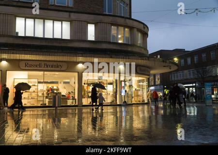 Exeter, Regno Unito, 16 novembre 2022: Al tramonto le vetrine dei negozi proiettano riflessi luminosi sui marciapiedi di Exeter mentre una banda di forti precipitazioni attraversava il Regno Unito. Molti negozi offrono sconti per il Black Friday e i rivenditori sono preoccupati che l'elevata inflazione, la recessione e il costo della crisi di vita creeranno un difficile ambiente commerciale per il settore retail. Anna Watson/Alamy Live News Foto Stock