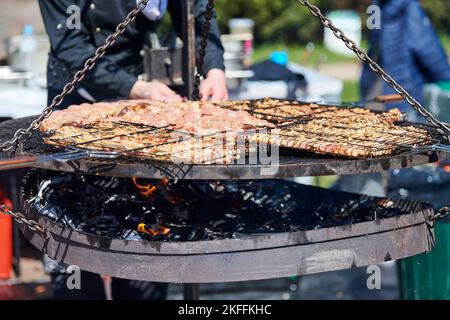 Cucina barbecue di pollo sul cestello barbecue con manico in legno, Street food e fast food festival. Grigliata di carne di pollo all'aperto in acciaio inox Foto Stock