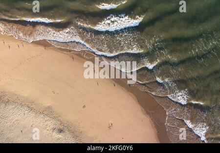 Veduta aerea delle onde e dei gabbiani che girovagano lungo Tenby South Beach a Tide, Galles, Regno Unito Foto Stock