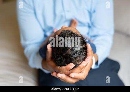 Un papà che tiene in mano il neonato, con un primo piano della testa e dei capelli del bambino Foto Stock