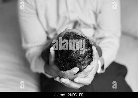 Un papà che tiene in mano il neonato, con un primo piano della testa e dei capelli del bambino Foto Stock