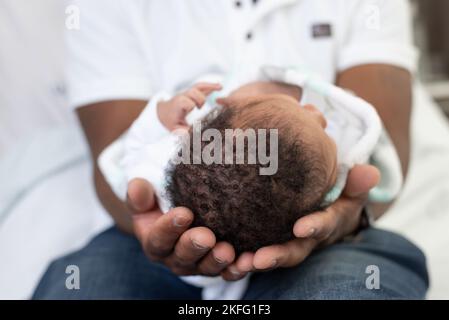 Un papà che tiene in mano il neonato, con un primo piano della testa e dei capelli del bambino Foto Stock