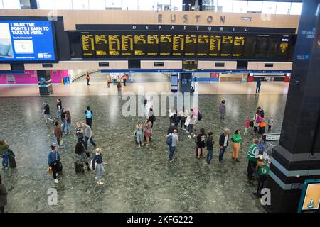 I passeggeri guardano il bordo elettrico alla stazione Euston di Londra il terzo giorno dello sciopero ferroviario. Foto Stock