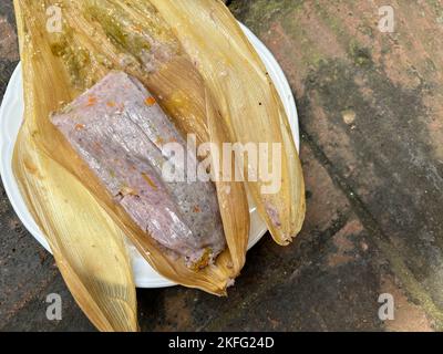 Tamale prodotto da mais blu con fiori di zucca avvolti in una buccia di mais a Oaxaca, Messico. Cibo Oaxacan fatto in casa. Foto Stock