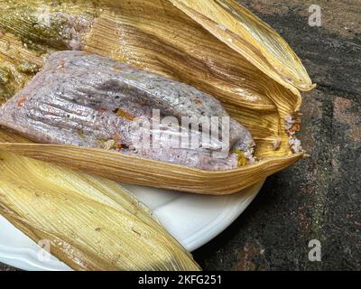 Tamale prodotto da mais blu con fiori di zucca avvolti in una buccia di mais a Oaxaca, Messico. Cibo Oaxacan fatto in casa. Foto Stock