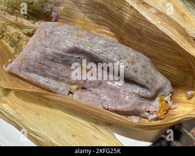 Tamale prodotto da mais blu con fiori di zucca avvolti in una buccia di mais a Oaxaca, Messico. Cibo Oaxacan fatto in casa. Foto Stock