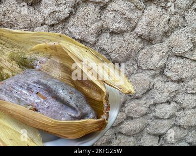 Tamale prodotto da mais blu con fiori di zucca avvolti in una buccia di mais a Oaxaca, Messico. Cibo Oaxacan fatto in casa. Foto Stock