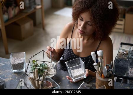 Focalizzata giovane donna fare un bel florarium nel suo laboratorio Foto Stock