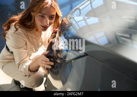 Cliente della concessionaria auto focalizzato che controlla la luce dell'auto Foto Stock