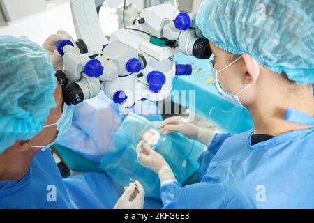 Dottore e assistente che eseguono l'operazione di correzione della visione laser Foto Stock