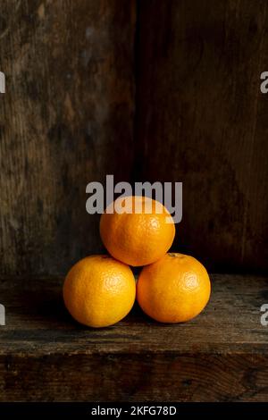 Tre arance fresche impilate su un tavolo in legno rustico Foto Stock