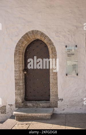 Estonia, Tallinn - 21 luglio 2022: Chiusura di una porta marrone chiusa in una parete beige che dà accesso alla torre del municipio Foto Stock