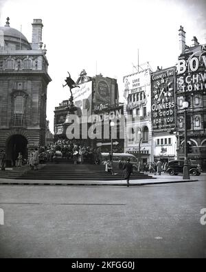 Anni '1949, Historial, una vista da quest'era del circo Piccadilly, Westminster, Londra, Inghilterra, Regno Unito, con persone che soggiornano presso la famosa fontana commemorativa di Shaftesbury. Popolarmente conosciuta come Eros, la fontana, con la sua statua alata di Anteros, fu eretta nel 1892 per commemorare l'opera caritatevole del VII conte di Shaftesbury. Nella foto si vedono anche alcuni dei famosi cartelloni pubblicitari che circondano il paesaggio del bivio stradale. Foto Stock