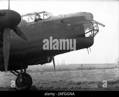 1948, storico, un pilota della RAF che sventola dall'abitacolo di un Avro Lancaster Bomber si è seduto su un campo a RAF Ternhill, Longford Camp, Market Drayton, Inghilterra, Regno Unito. Progettato da Roy Chadwick, il Lancaster era un bombardiere pesante del WW2 realizzato da Avro (A.V. Roe and Company), un produttore britannico fondato nel 1910 a Manchester, Lancashire, Inghilterra, Regno Unito. Il prototipo della Lancaster fece il suo primo volo nel gennaio 1941. L'aeromobile aveva un equipaggio di sette membri, con un'età media di soli 22 anni. Foto Stock