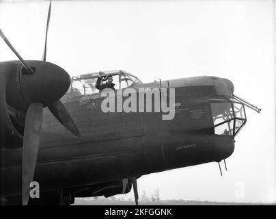 1948, storico, un pilota della RAF che sventola dall'abitacolo di un Avro Lancaster Bomber a RAF Ternhill, Longford Camp, Market Drayton, Inghilterra, Regno Unito. Progettato da Roy Chadwick, il Lancaster era un bombardiere pesante del WW2 realizzato da Avro (A.V. Roe and Company), un produttore britannico fondato nel 1910 a Manchester, Lancashire, Inghilterra, Regno Unito. Il prototipo della Lancaster fece il suo primo volo nel gennaio 1941. L'aeromobile aveva un equipaggio di sette membri, con un'età media di soli 22 anni. Foto Stock