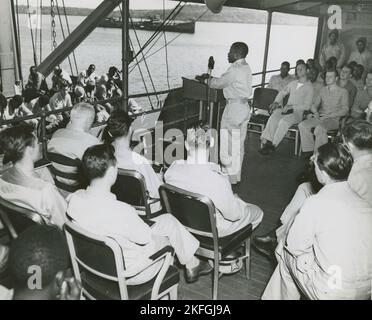 Cappellano afroamericano in piedi sul podio e dirigente il servizio religioso sul ponte di una nave della Guardia Costiera degli Stati Uniti, Sud Pacifico, 1939 - 1945. Foto Stock