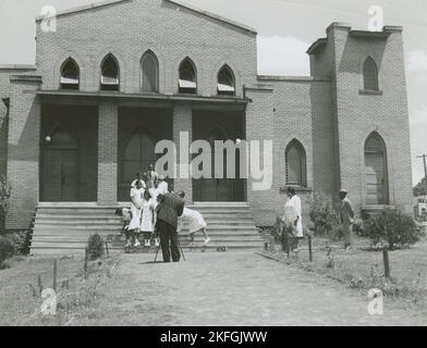 Uscieri di una chiesa afroamericana in piedi sui gradini della chiesa e preparandosi a posare per un fotografo, Durham, Carolina del Nord, maggio 1940. Foto Stock