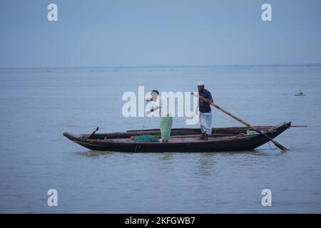 Due persone stanno pescando hilsa nel fiume in barca. Foto Stock