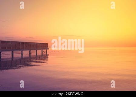 Molo nella nebbia marina all'alba dorata Foto Stock