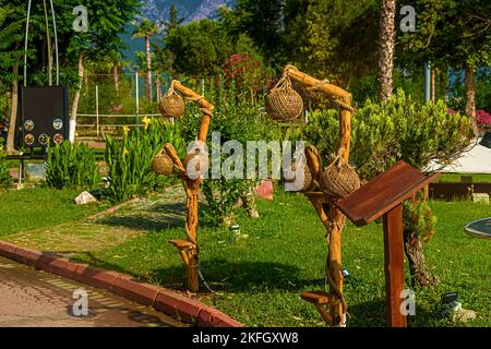 Vista del sentiero e delle lanterne di legno lungo il sentiero in un giardino verde con alberi verdi lungo l'argine di Kemer Foto Stock