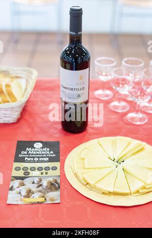 Formaggio. È venuto. Piatto di formaggio di pecora. Bottiglia di vino rosso. Triangolo formaggio. Fotografia verticale. Foto Stock