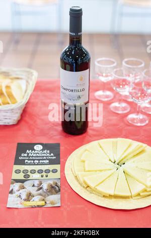 Formaggio. È venuto. Piatto di formaggio di pecora. Bottiglia di vino rosso. Triangolo formaggio. Fotografia verticale. Foto Stock