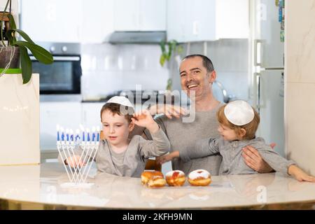 Padre e figli con la menorah celebrano hanukkah - festa religiosa ebraica Foto Stock