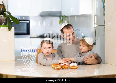 Padre e figli con la menorah celebrano hanukkah - festa religiosa ebraica Foto Stock