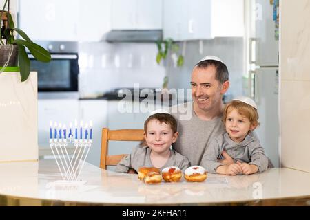 Padre e figli con la menorah celebrano hanukkah - festa religiosa ebraica Foto Stock