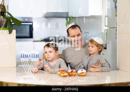 Padre e figli con la menorah celebrano hanukkah - festa religiosa ebraica Foto Stock