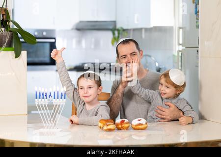 Padre e figli con la menorah celebrano hanukkah - festa religiosa ebraica Foto Stock