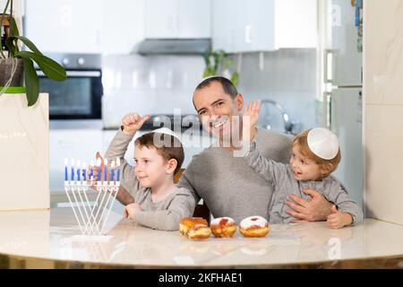 Padre e figli con la menorah celebrano hanukkah - festa religiosa ebraica Foto Stock