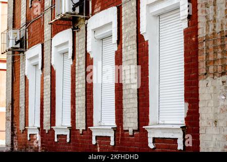 Finestre Brick House con serranda rotante per la protezione della casa. Foto Stock