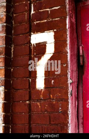 Numero 7 sette sul muro di mattoni rossi della casa. Foto Stock