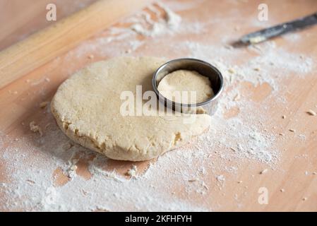 La miscela di Scone è stata arrotolata sul piano di lavoro con un utensile circolare per tagliare la forma prima di cuocere in forno. Foto Stock
