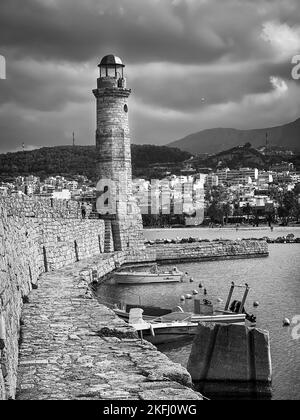 Vista dello storico faro di la Canea al porto sull'isola di Creta contro la città e il cielo nuvoloso durante la tempesta Foto Stock