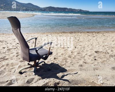 Poltrona vuota abbandonata sulla spiaggia sabbiosa contro il mare e il cielo azzurro limpido nelle giornate di sole Foto Stock