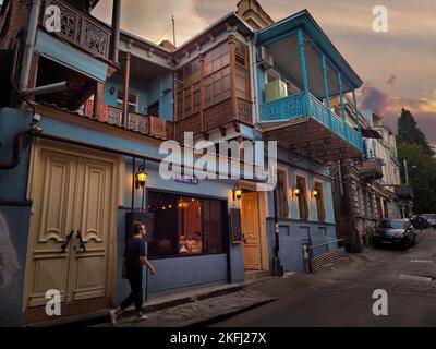 Tbilisi, Georgia - 07 23 2022: Un passerby maschile che cammina lungo la strada Lado Asatiani accanto a un caffè che offre cucina georgiana e vino Foto Stock