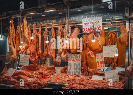 Stand del fornitore locale con diversi tipi di incontro appesi nel mercato municipale centrale di Atene con le etichette dei prezzi allegate. Foto Stock