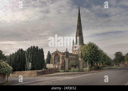 St Oswald's Church, Ashbourne, Derbyshire, Regno Unito. Taken on 5 ottobre 2019. Vecchia chiesa in pietra con guglia sul lato della strada di campagna. Foto Stock
