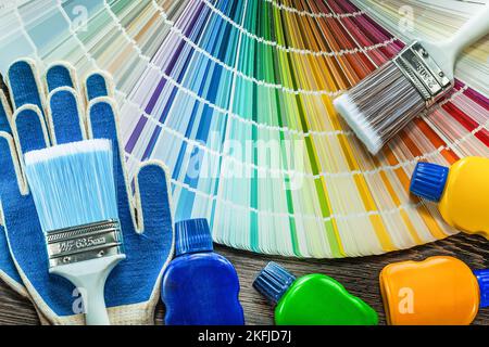 Assortimento di guanti di protezione vernice bottiglie pennello colore palette su legno. Foto Stock