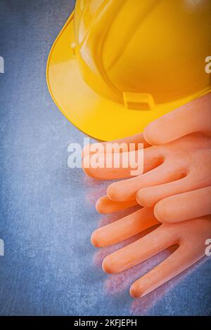 Guanti isolanti in gomma che costruiscono il casco su sfondo metallico. Foto Stock