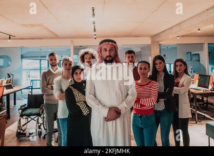 Un gruppo eterogeneo di persone di successo in un moderno ufficio di vetro si trova al vertice con il loro leader arabo direttore Foto Stock