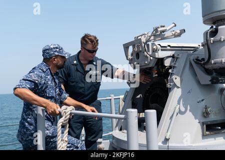 220920-N-ZA692-1361 GOLFO ARABICO (SETT. 20, 2022) Gunner’s Mate 1st Class Nathan Rattelade conduce l’addestramento del sistema di mitragliatrici MK 38 Mod 2 25mm a bordo della nave costiera di pattuglia USS Chinook (PC 9) con il personale della Royal Bahrain Naval Force nel Golfo Arabico, settembre 20. Chinook ha condotto uno scambio professionale di tre giorni che si è concluso il 21 settembre. Foto Stock