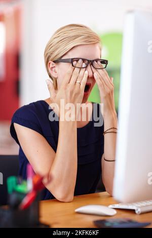 Alcuni giorni sembrano più lunghi di altri. Una giovane donna d'affari che guarda stanca mentre strofina gli occhi. Foto Stock