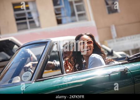 Viaggiare è vivere. Una giovane coppia felice che guida in una cabriolet in una giornata di estati luminose. Foto Stock