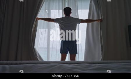 Persona che apre le tende della finestra di mattina per ottenere la luce di giorno a casa Foto Stock