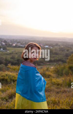 Donna felice in vestito lungo che tiene una bandiera gialla e blu dell'Ucraina Foto Stock